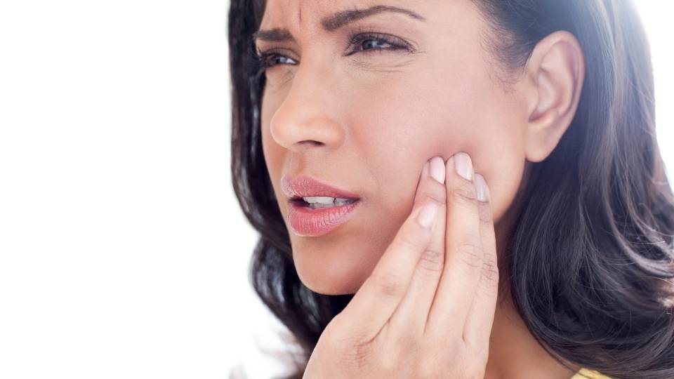 Woman with jaw pain holding jaw